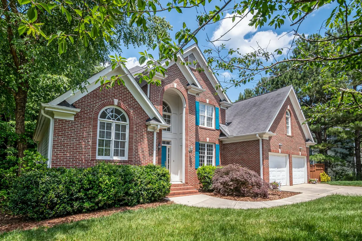 Red brick home exterior with blue shutters and landscaped front lawn